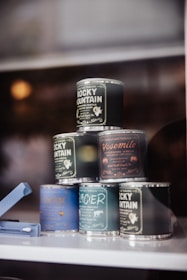 A set of small-batch packaging tins with custom artwork displayed on a wooden table.