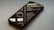 A smartphone lies on its back on a smooth surface, displaying lines of code and programming text on its screen. The screen brightness creates a soft glow, and the reflection shows the text in reverse. The phone is angled slightly to the side, partially out of focus.