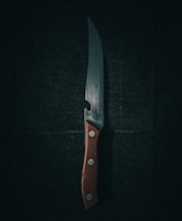 A close-up of a chef's knife with a wooden handle.