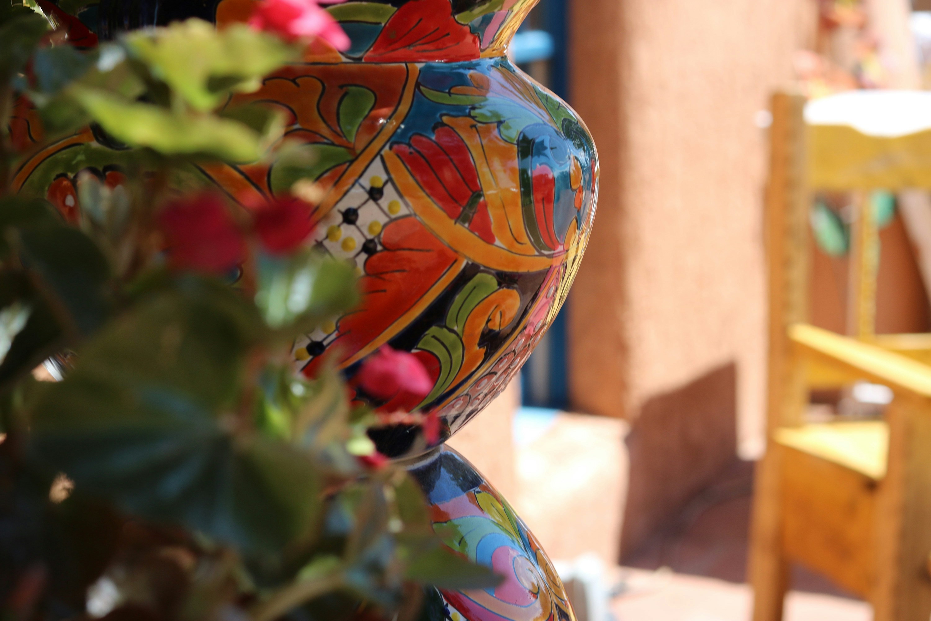 red and green artificial flowers in clear glass vase, Pottery in an open air market in New Mexico.