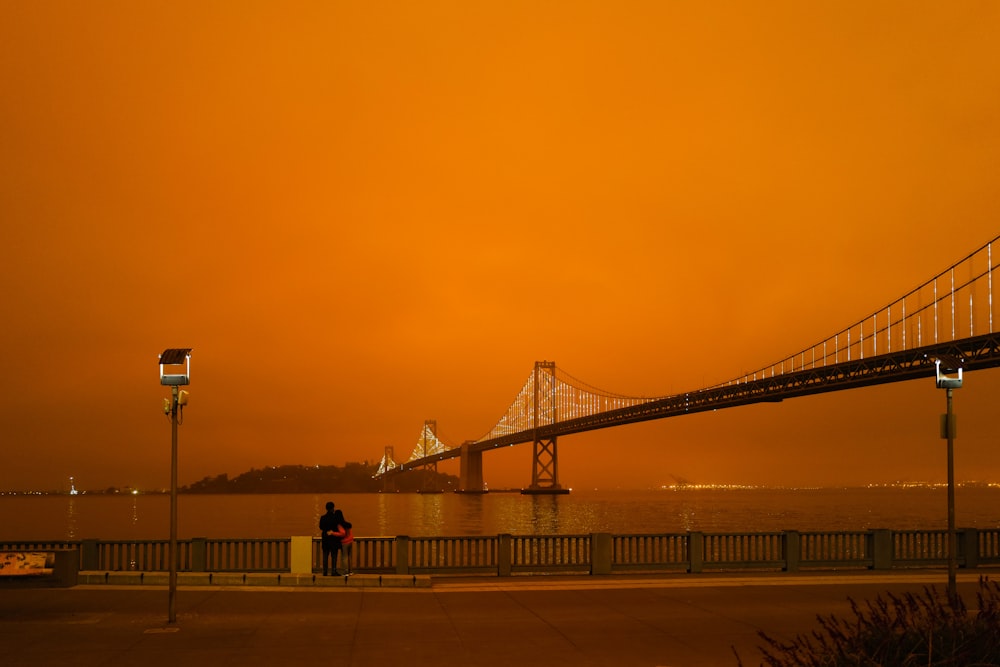 silhouette of people walking on bridge during sunset