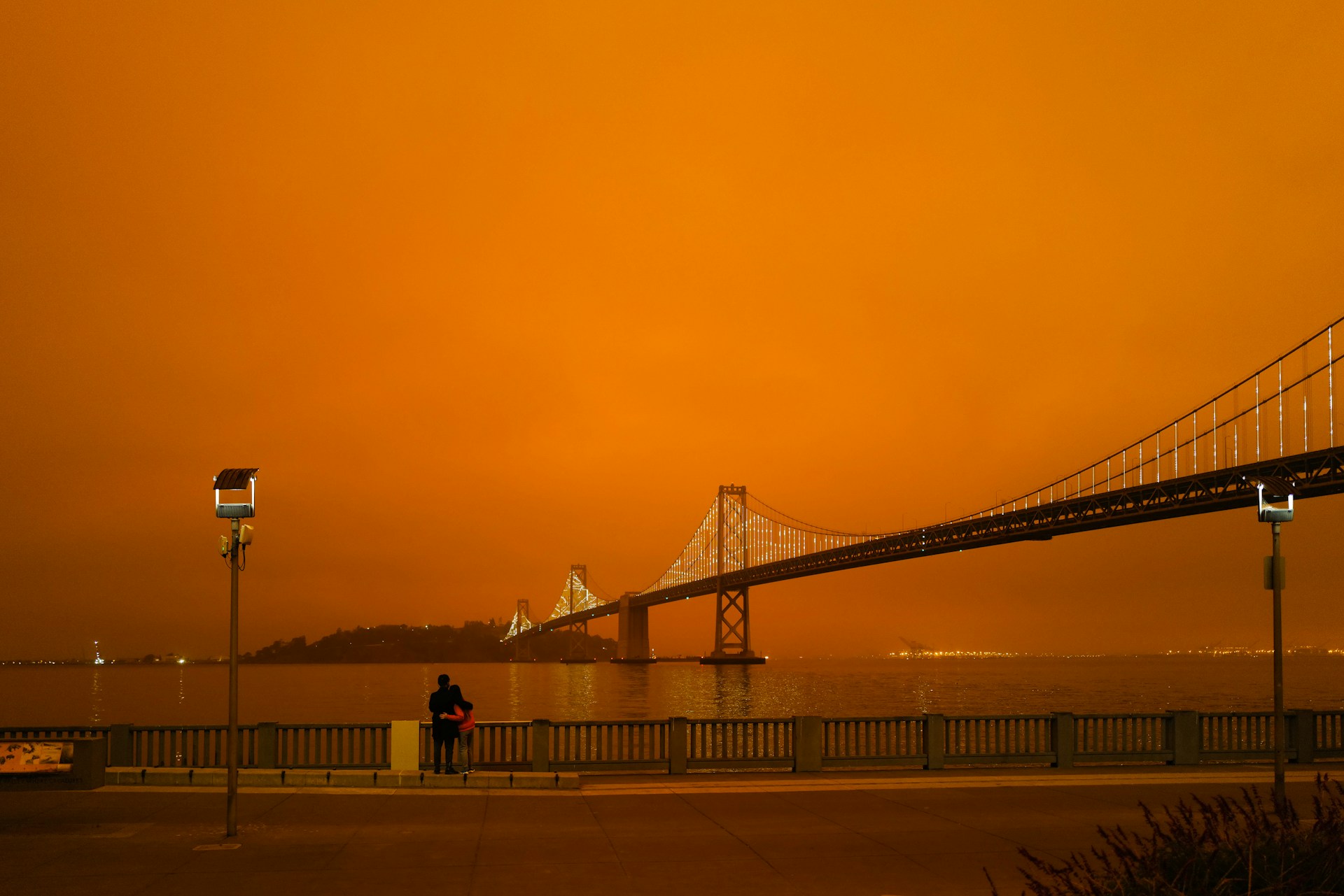 silhouette of people walking on bridge during sunset