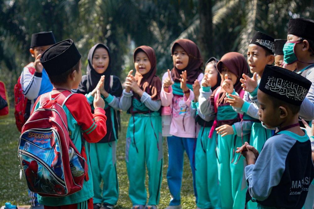 children in green long sleeve shirt standing on green grass field during daytime