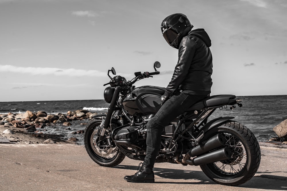 man in black leather jacket riding black and red motorcycle