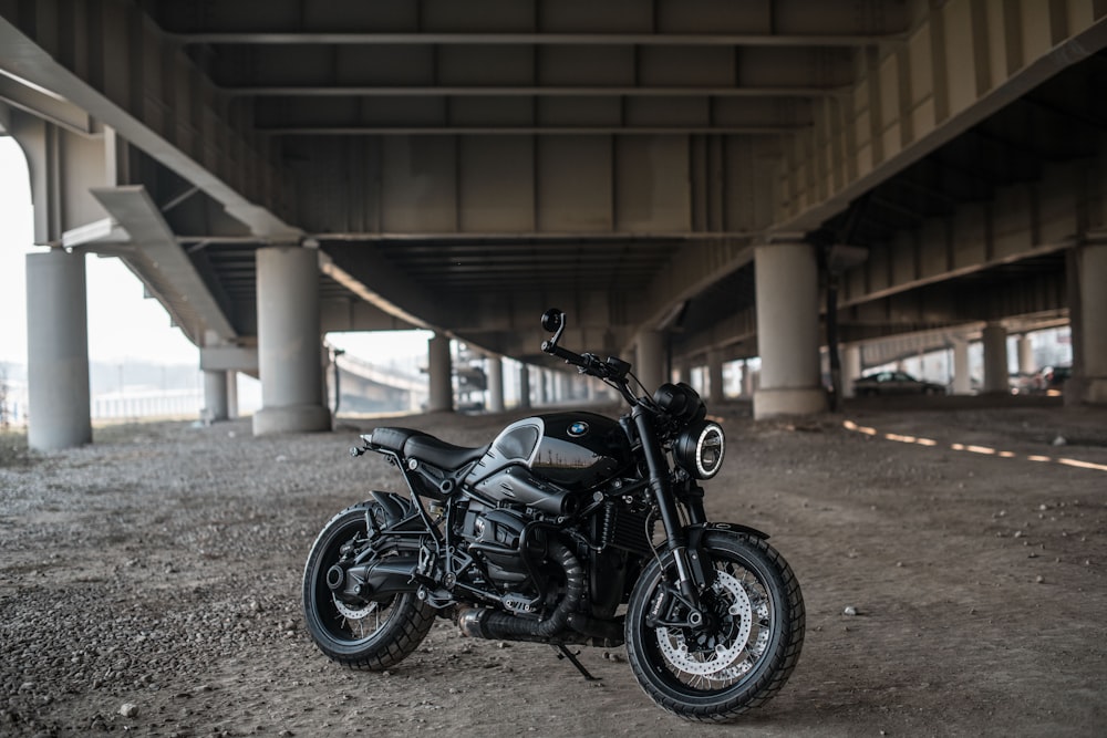 black motorcycle parked beside gray concrete building during daytime