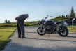A rider inspecting a motorcycle in a scenic outdoor setting.