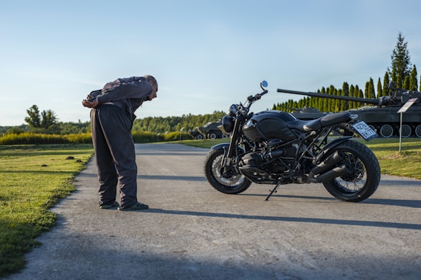 A mechanic carefully inspecting a motorcycle engine outdoors.