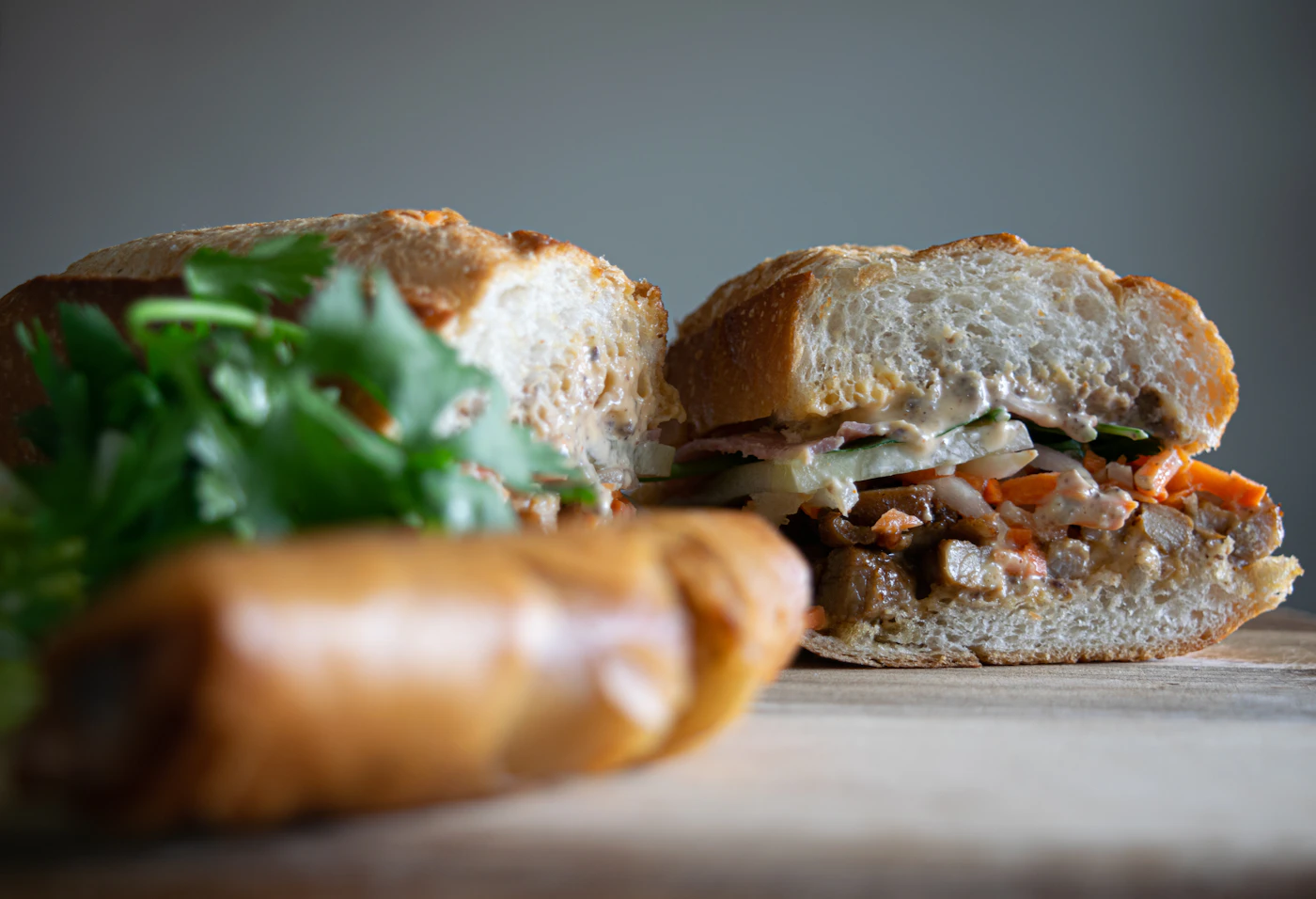 Caramel pork bánh mì sandwich in a crisp baguette with pickled carrot and daikon, cucumber, cilantro, and chile mayonnaise