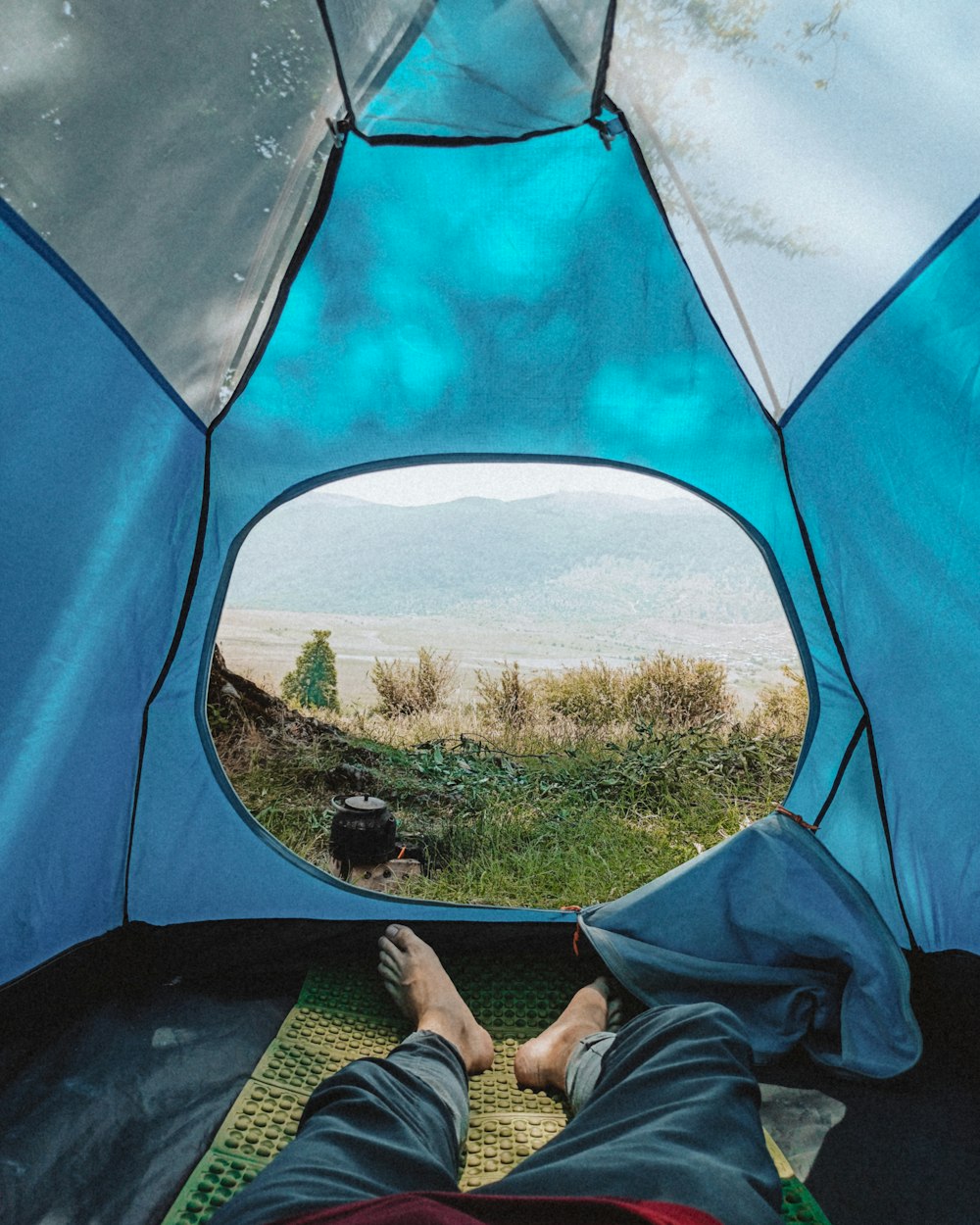 person in blue pants sitting inside blue tent