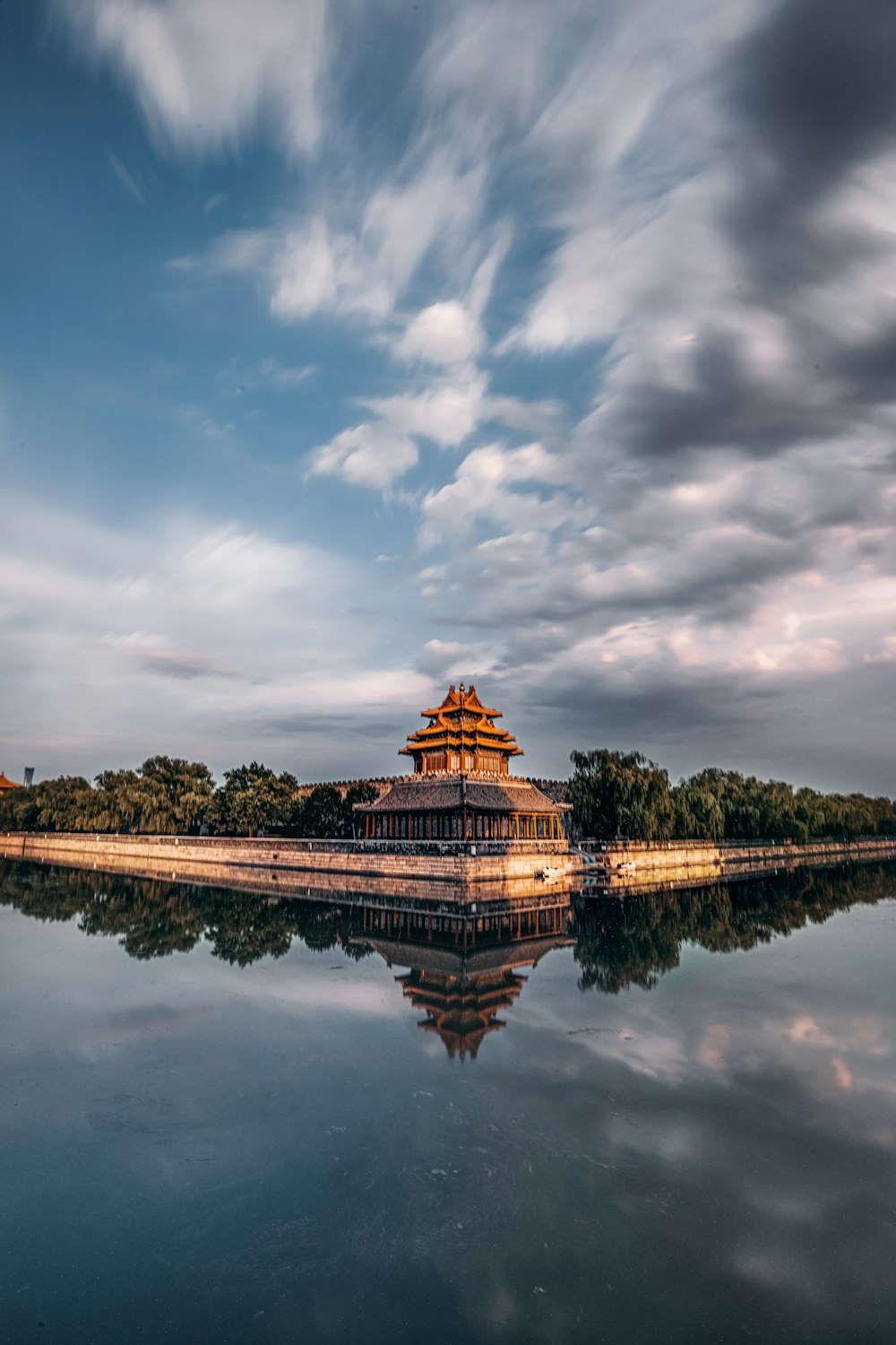 brown and green temple near body of water under cloudy sky during daytime