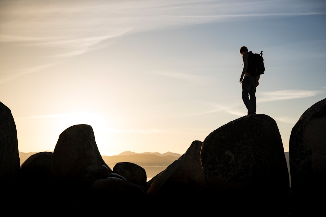 silhouette of man standing on rock formation during daytime