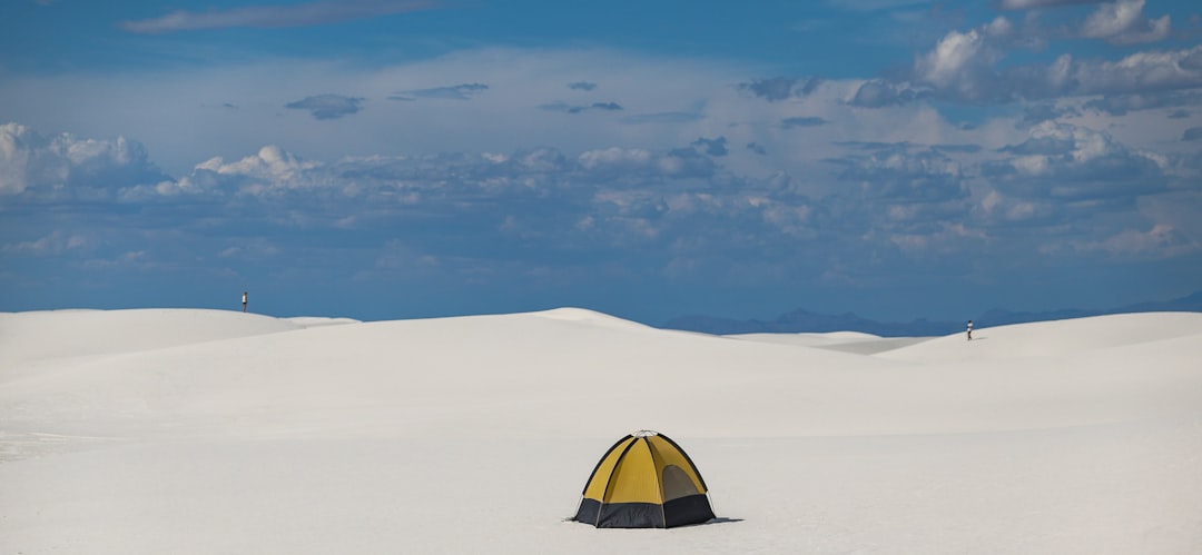 yellow and black dome tent on white snow covered ground under blue and white sunny cloudy