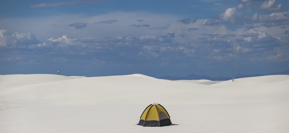 yellow and black dome tent on white snow covered ground under blue and white sunny cloudy