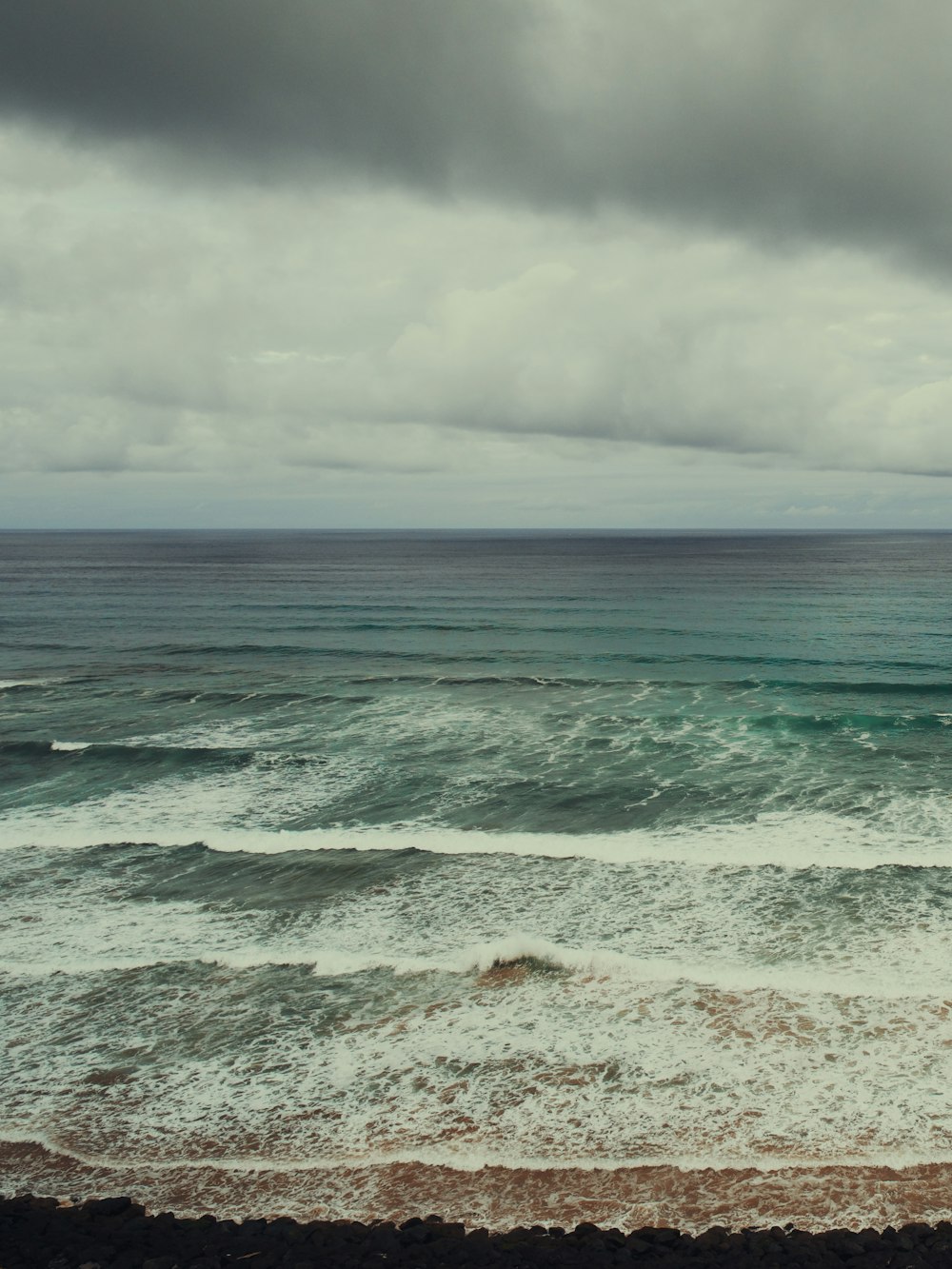 sea waves crashing on shore under white clouds during daytime