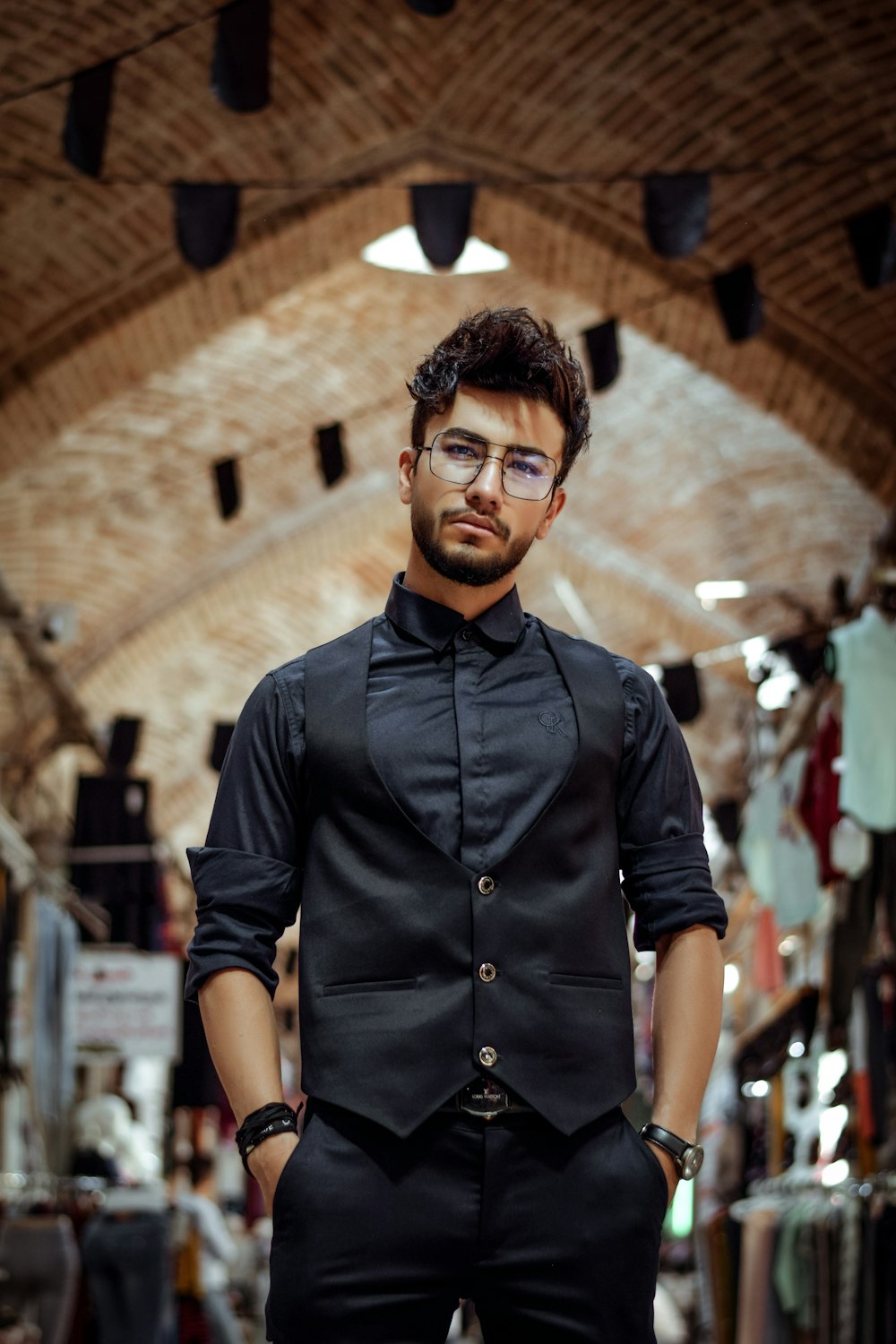 man in black button up shirt standing near brown brick wall