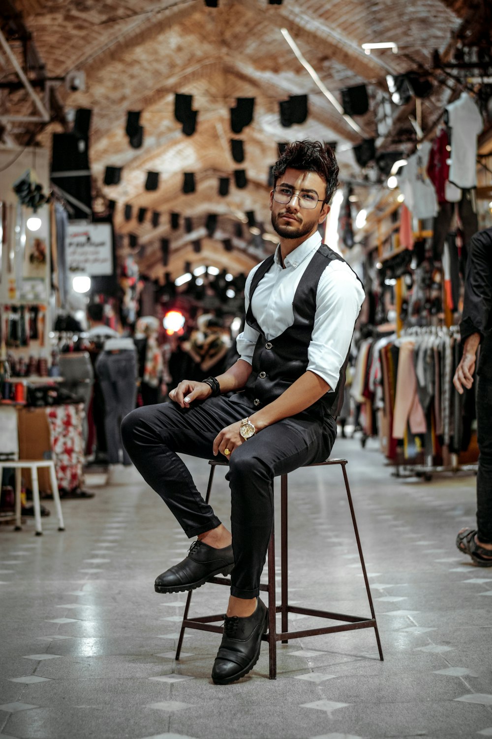 Homme en polo blanc et noir et pantalon noir assis sur une chaise