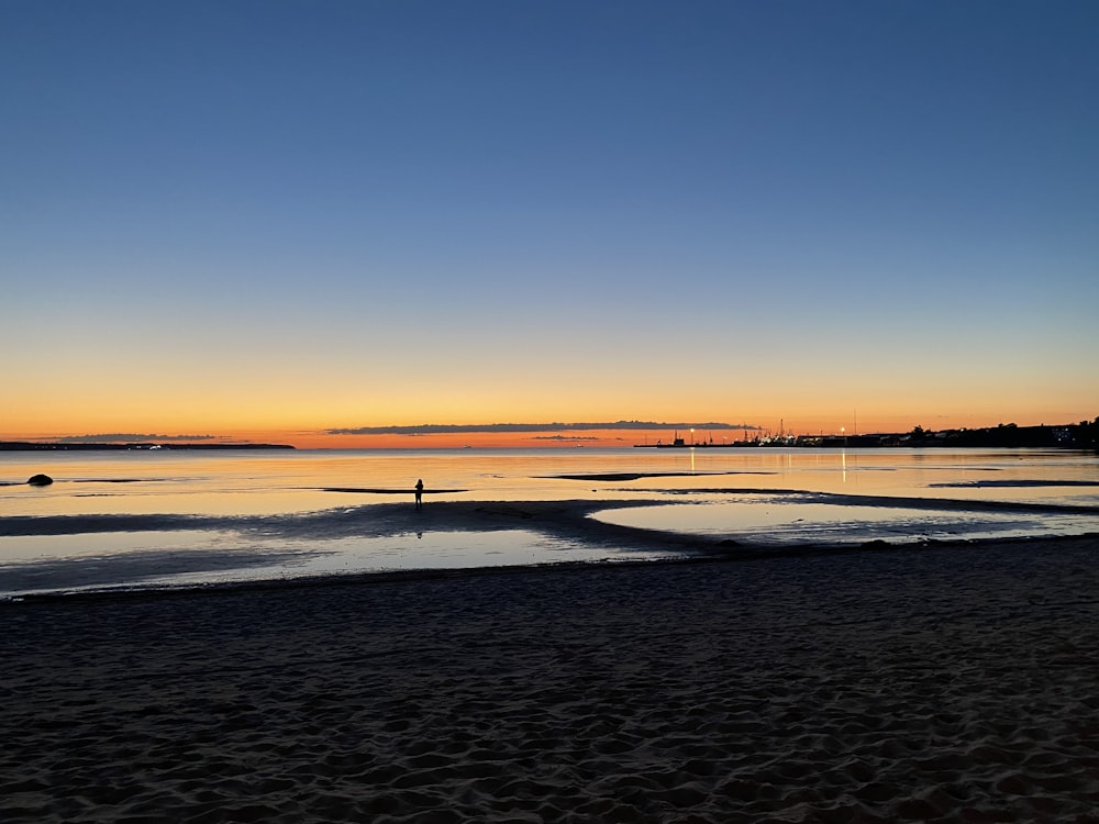 Person, die bei Sonnenuntergang am Strand spazieren geht