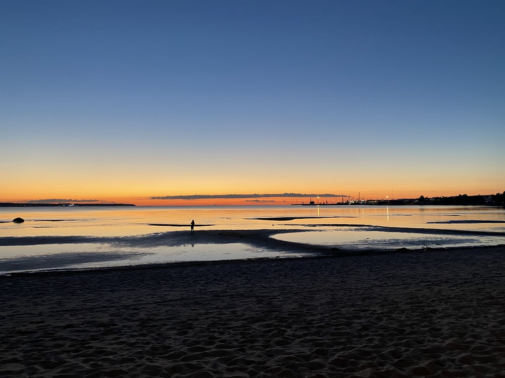 person walking on beach during sunset