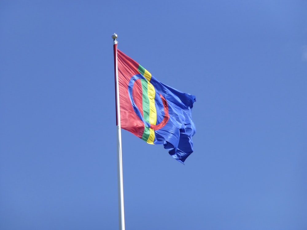 a flag flying in the wind with a blue sky in the background