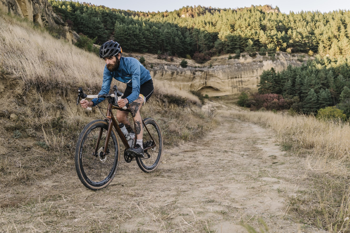 Tattooed cyclist riding a gravel bike in a forest