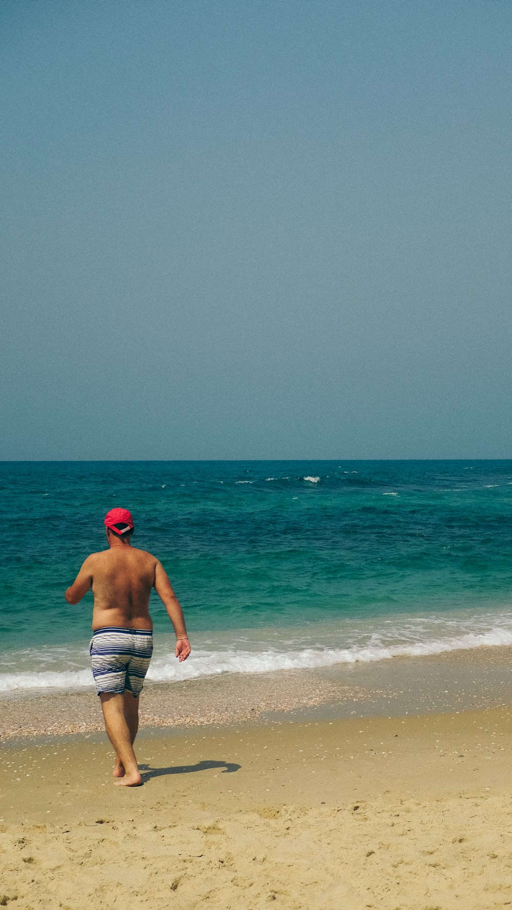 man in white and blue shorts standing on beach during daytime