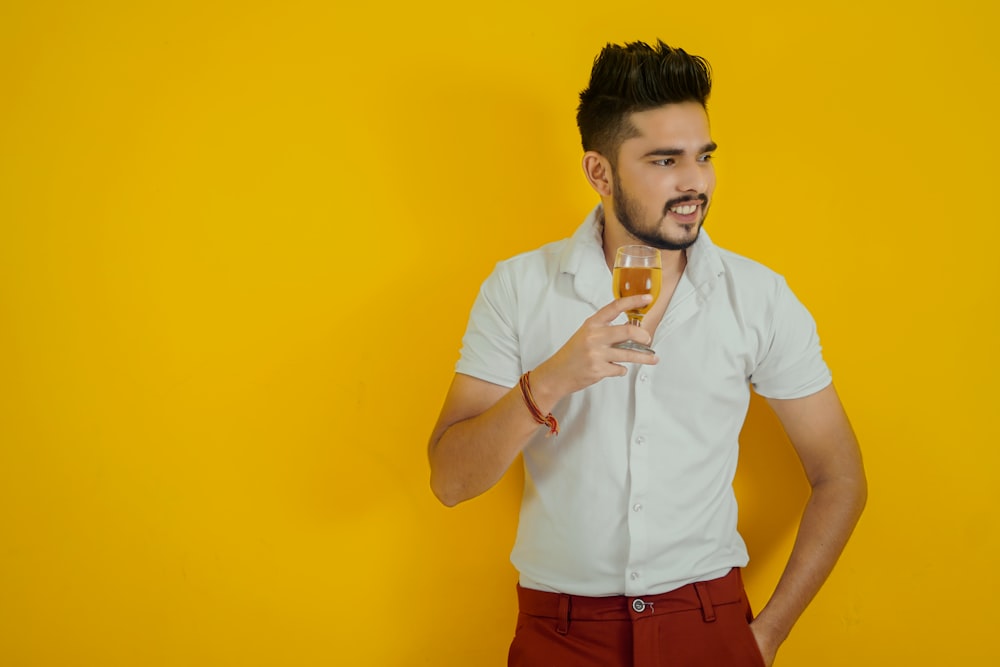 man in white button up shirt and red denim shorts holding clear drinking glass