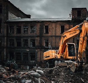 yellow excavator near brown concrete building during daytime