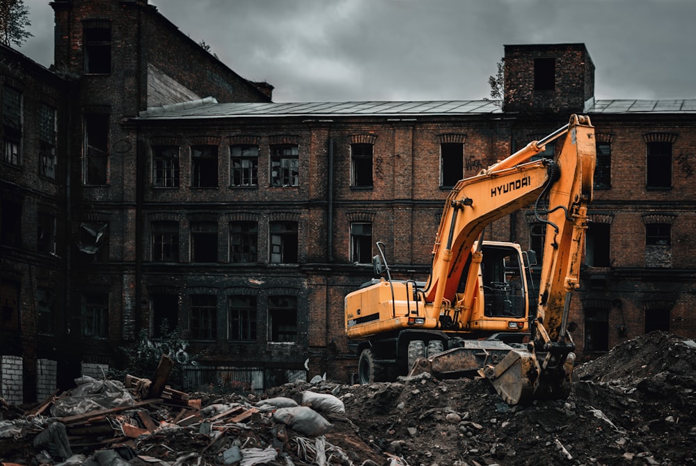 Gelber Bagger in der Nähe von braunem Betongebäude tagsüber