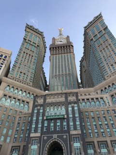 A large and intricately designed building with a prominent clock tower at the center, flanked by two symmetrical wings. The architecture features a mix of modern and traditional elements, with numerous windows and decorative arches.