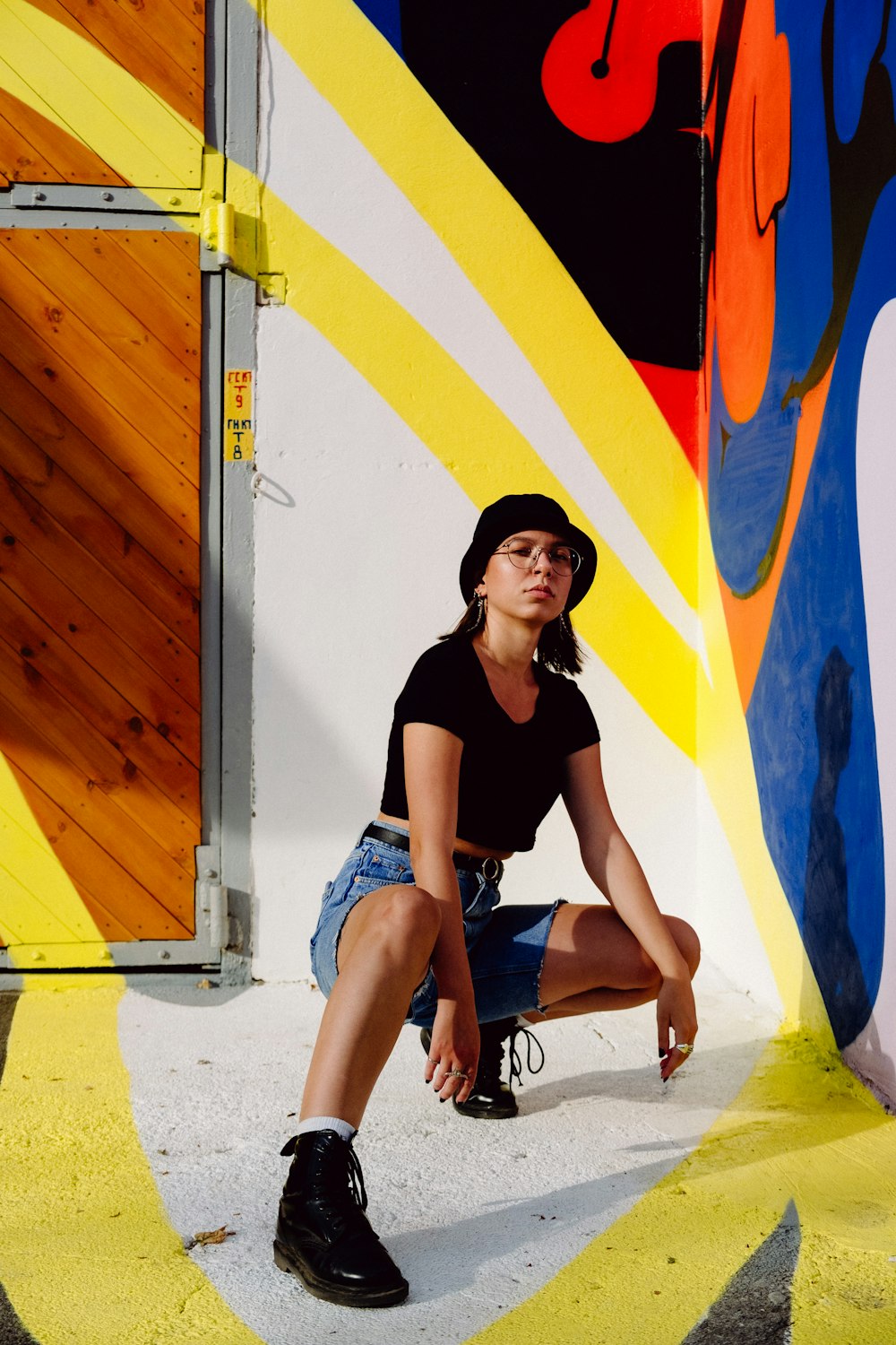 woman in black shirt and blue denim shorts sitting on white concrete bench during daytime