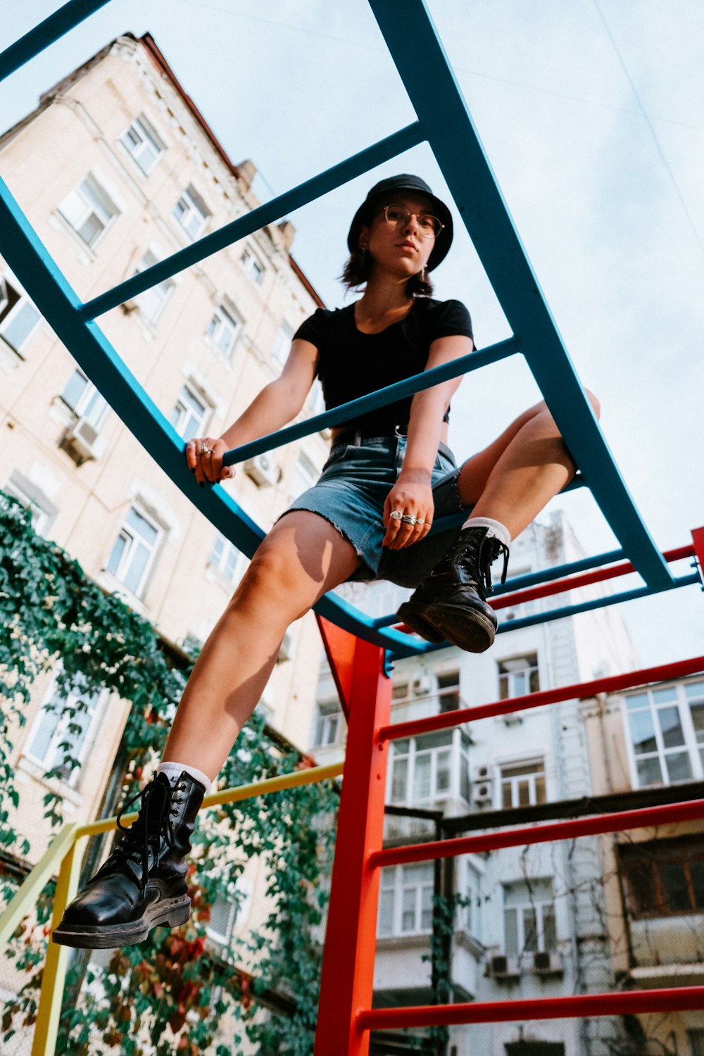 woman in black t-shirt and black shorts sitting on blue metal bar during daytime