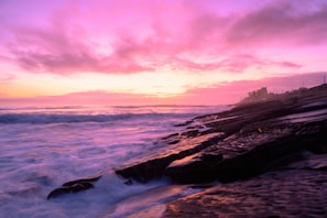 Golden sunset over the cliffs of Algarve with waves gently crashing below.