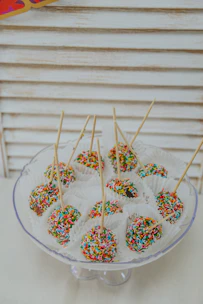 A vibrant assortment of colorful cake pops and caramel apples arranged on a festive birthday table.