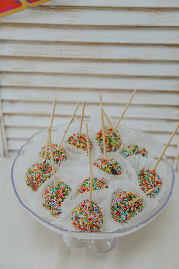 Close-up of colorful, glossy cake pops arranged on a rustic wooden board.