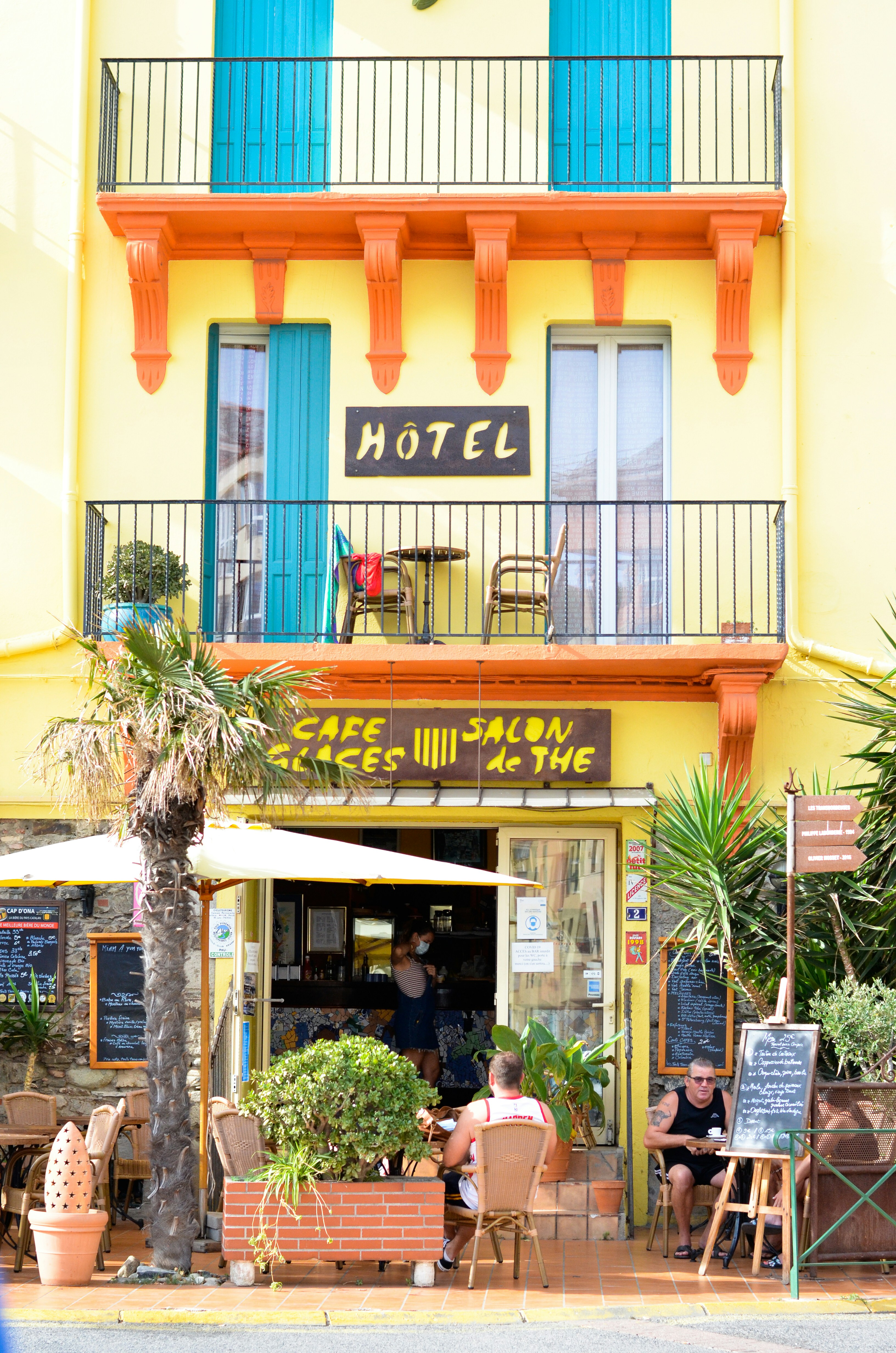 Palmier vert devant un bâtiment en béton brun et blanc pendant la journée