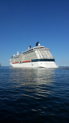 A panoramic view of a cruise ship cutting through calm, deep blue waters.