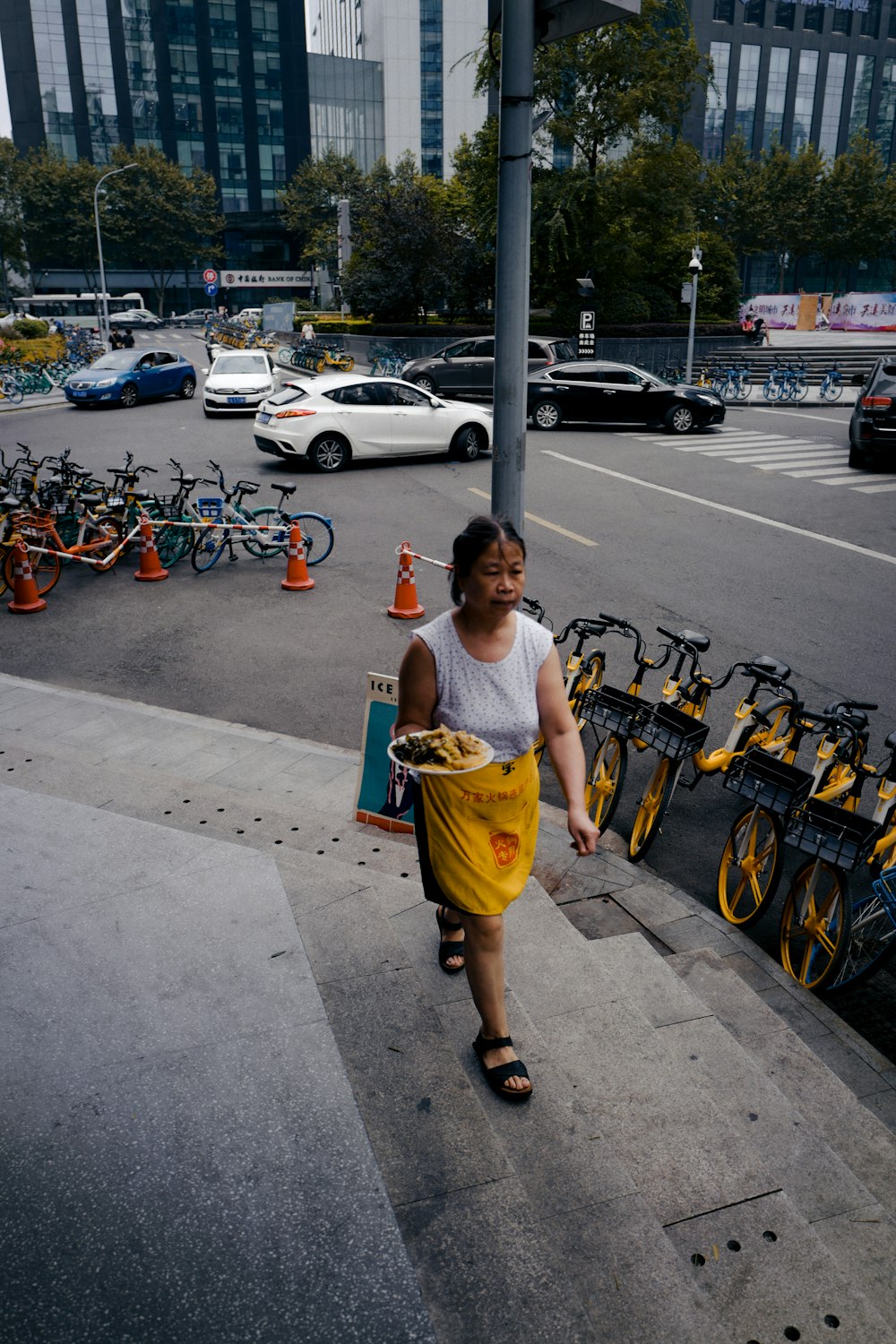 girl in blue tank top and yellow skirt standing on sidewalk during daytime