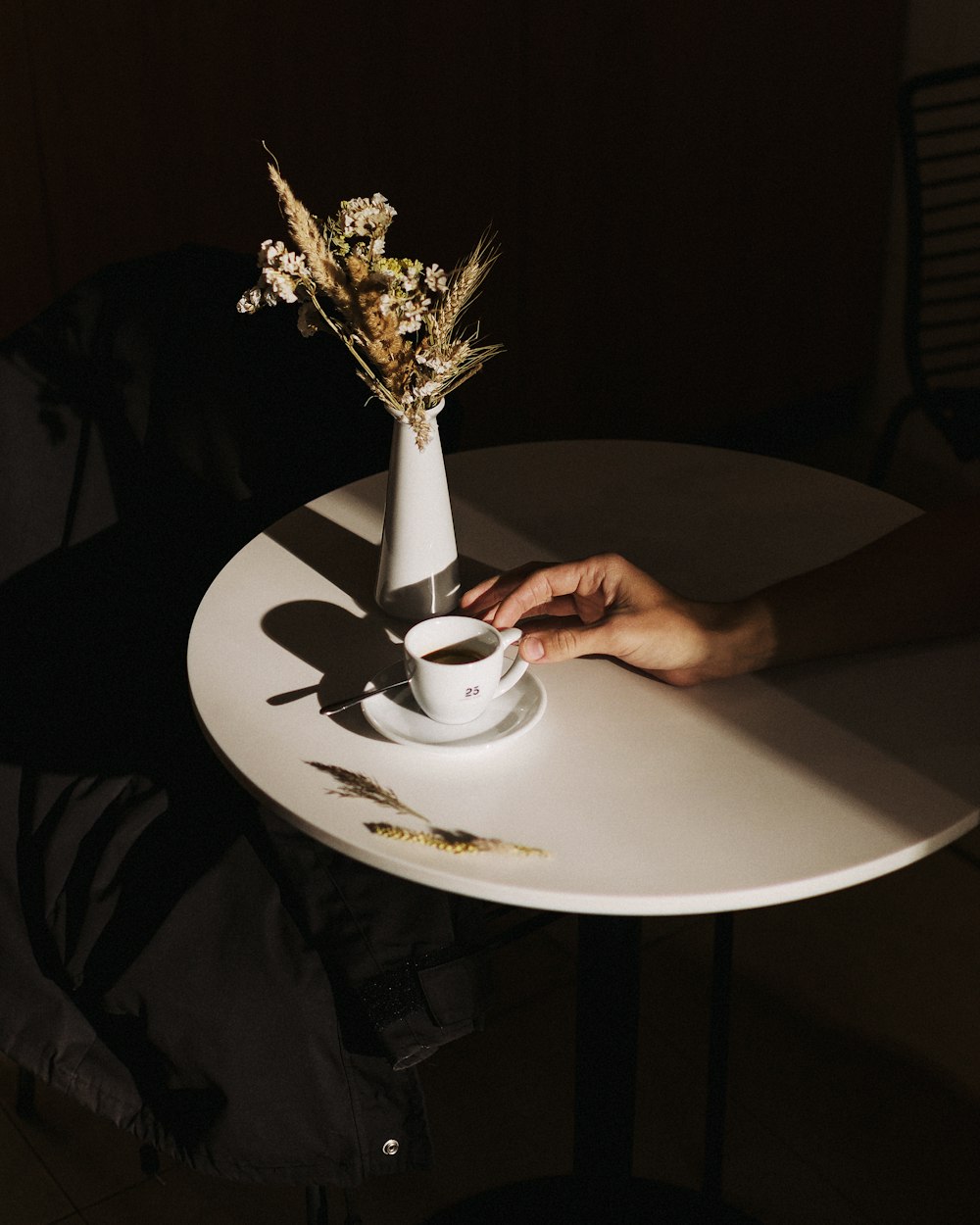 person holding white ceramic mug on white round table