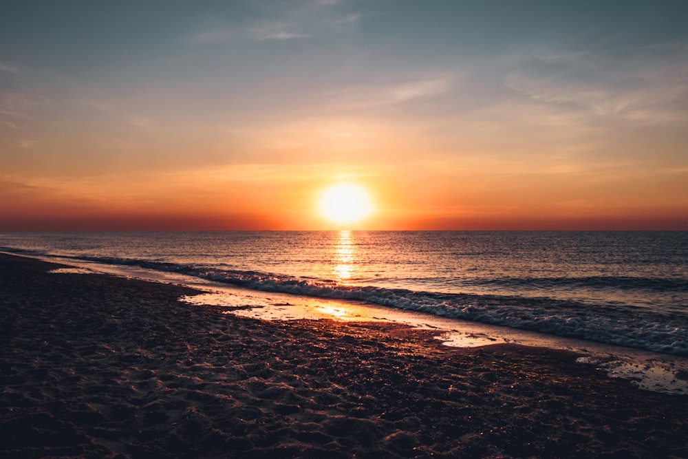 sea waves crashing on shore during sunset