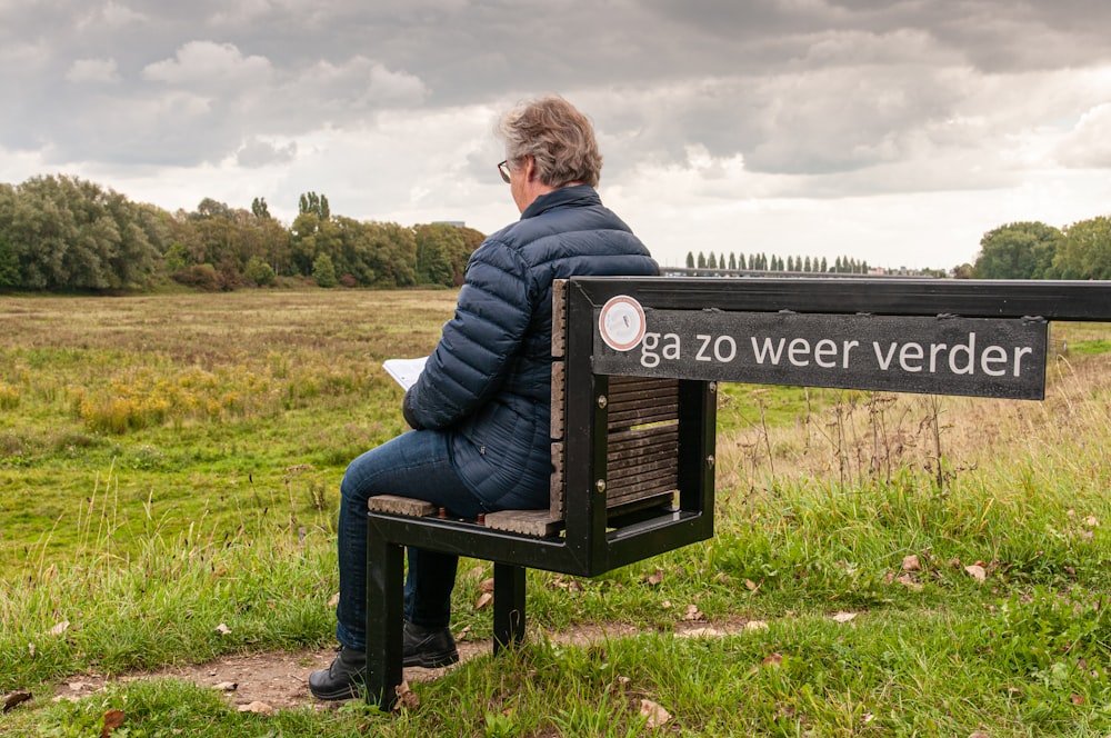 woman in blue jacket sitting on black wooden bench