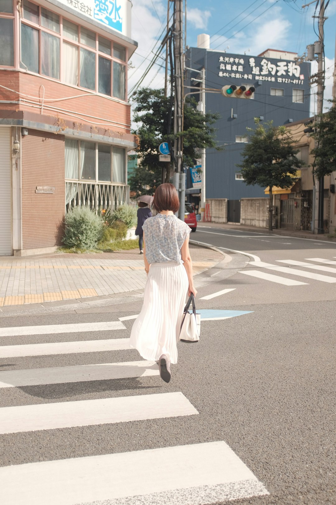 woman in white and red dress walking on pedestrian lane during daytime