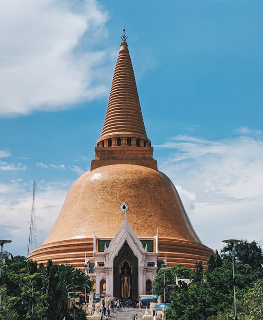 gold and white concrete building under blue sky during daytime in Phra Pathom Chedi Thailand