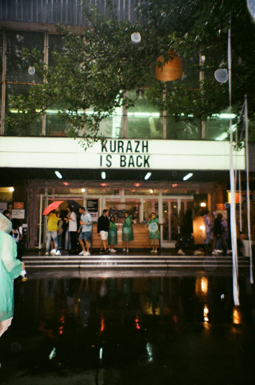 people walking near white and green building during night time