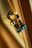 A LEGO figure with glasses and a black outfit is holding a wand while hanging from a golden cord.