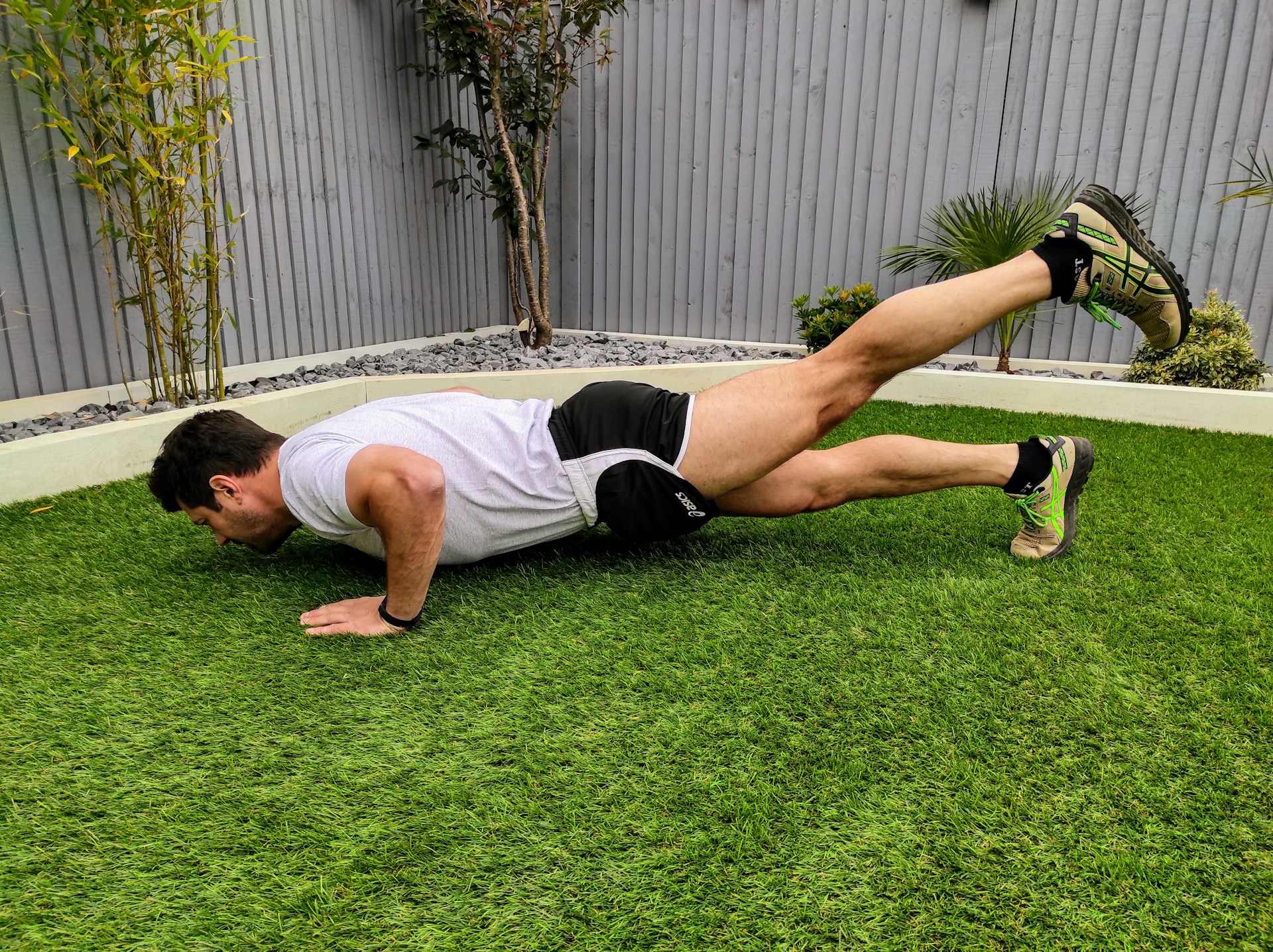 man in white tank top and black shorts lying on green grass field during daytime