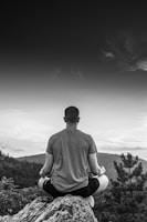 A serene landscape with a person meditating to music.