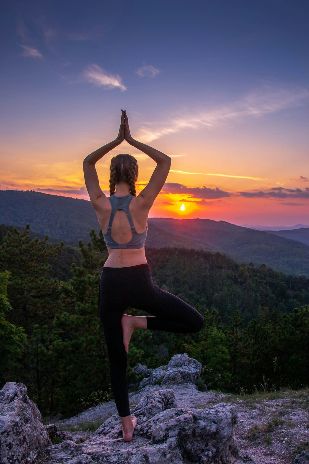 woman in black leggings standing on rock formation during sunset