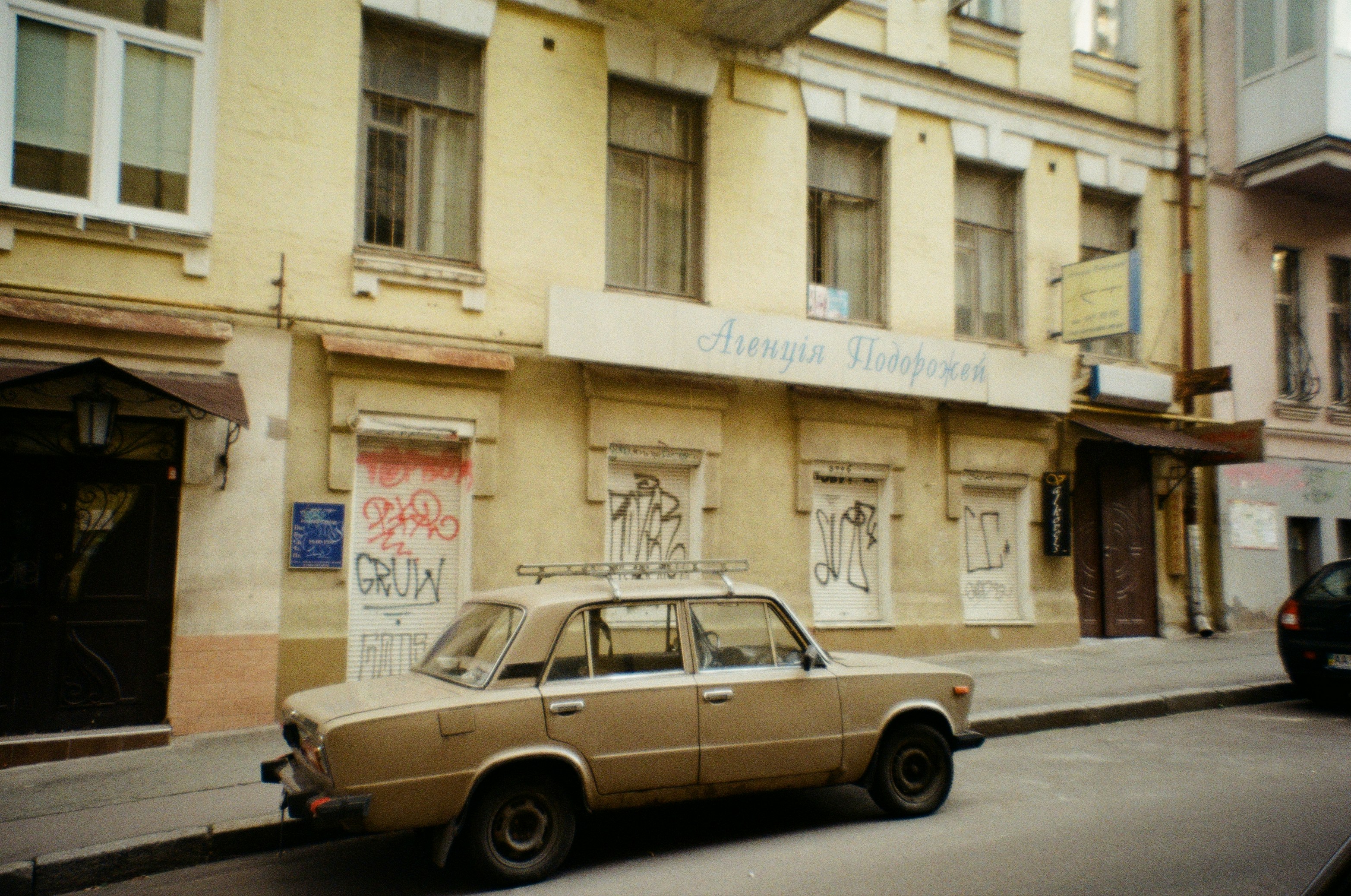 Station wagon marrone parcheggiata accanto all'edificio di cemento bianco durante il giorno