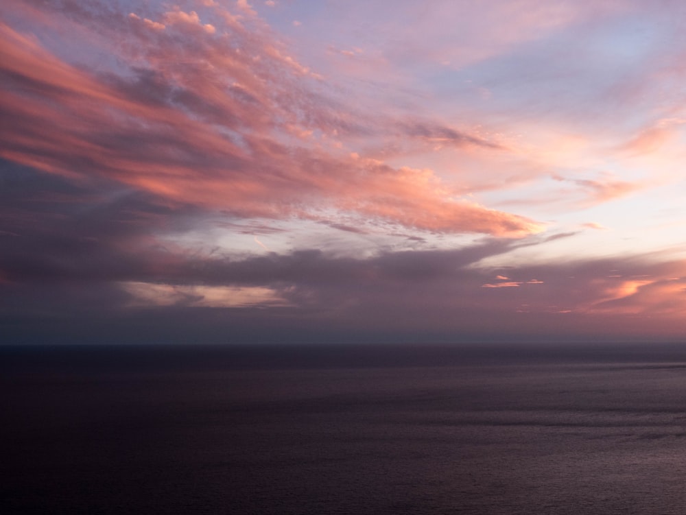 body of water under cloudy sky during sunset