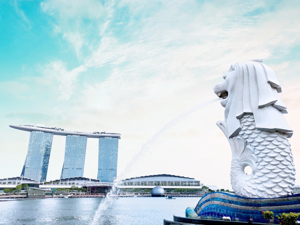 white concrete building near water fountain under white clouds during daytime